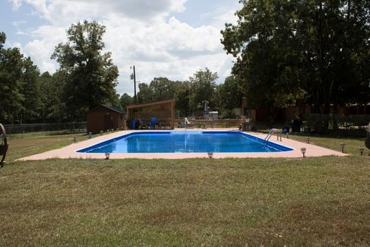 In-ground pool with blue water, pink deck, and pergola